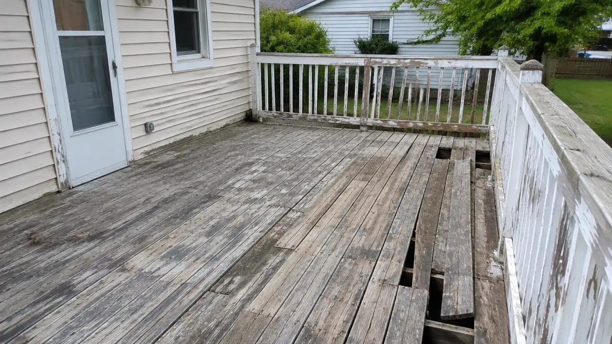 Weathered back deck with loose boards and peeling railing