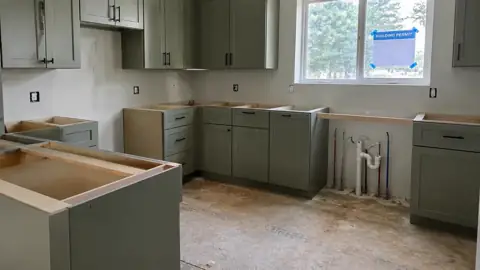 Half-finished kitchen remodel with no countertops and a building permit on the window