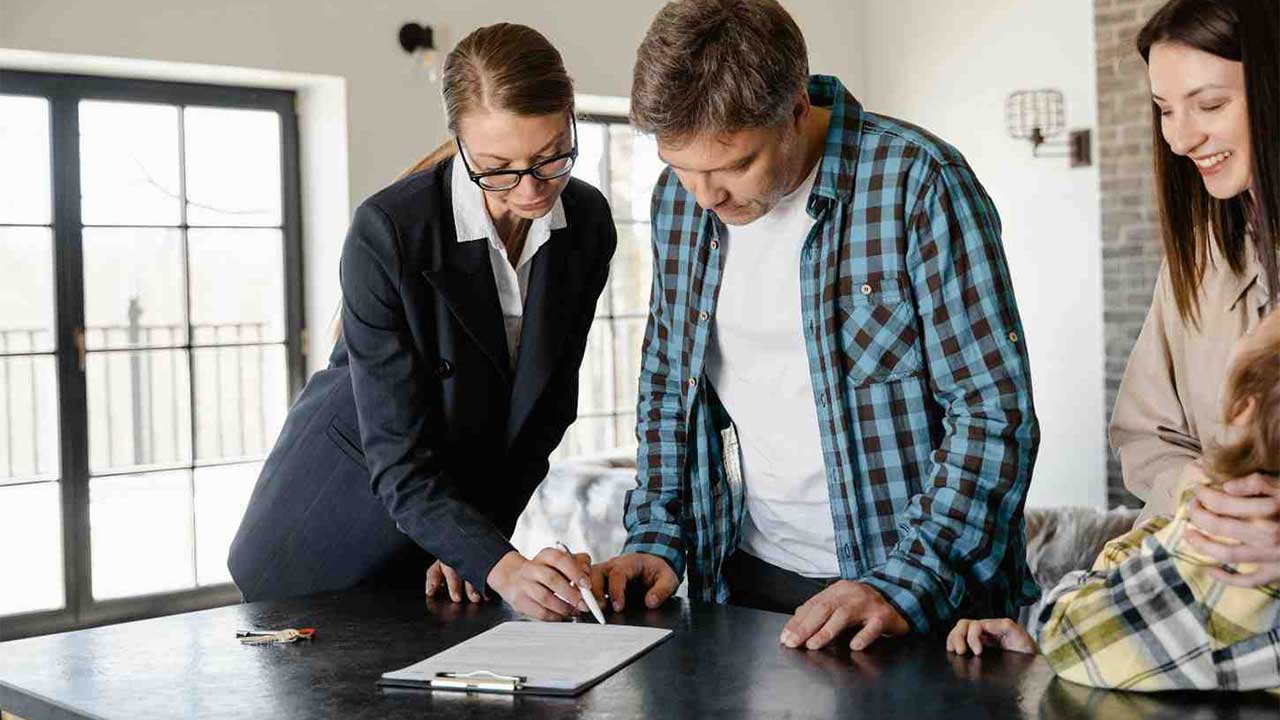 A real estate agent assists a couple in reviewing the documents they need to sell their house quickly and legally